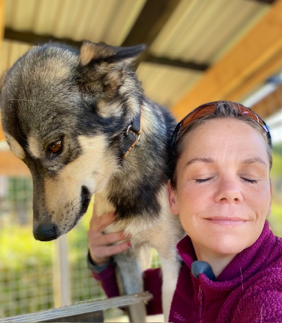 Lene holder Balto tett inntil seg i hundegården
